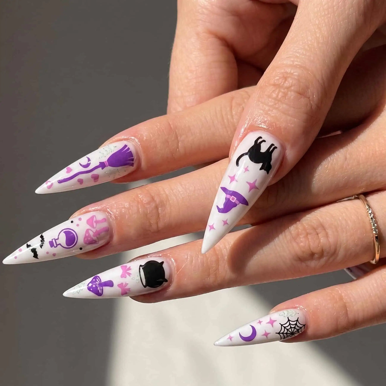 halloween stiletto press on nails worn look, pink witch, black cat, potion, and moon