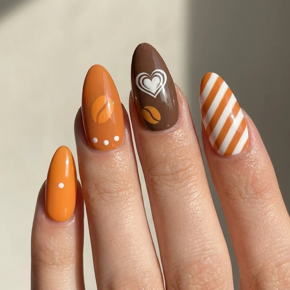 Coffee Crush short almond press-on nails worn on hand — coffee cup, beans, caramel stripes, and heart art